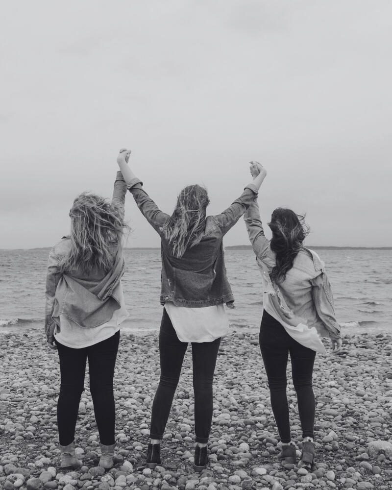 3 women on a beach holding hands
